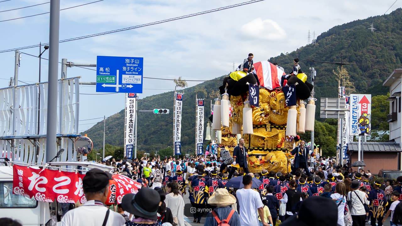 Golden taiko float parading through town with large crowds